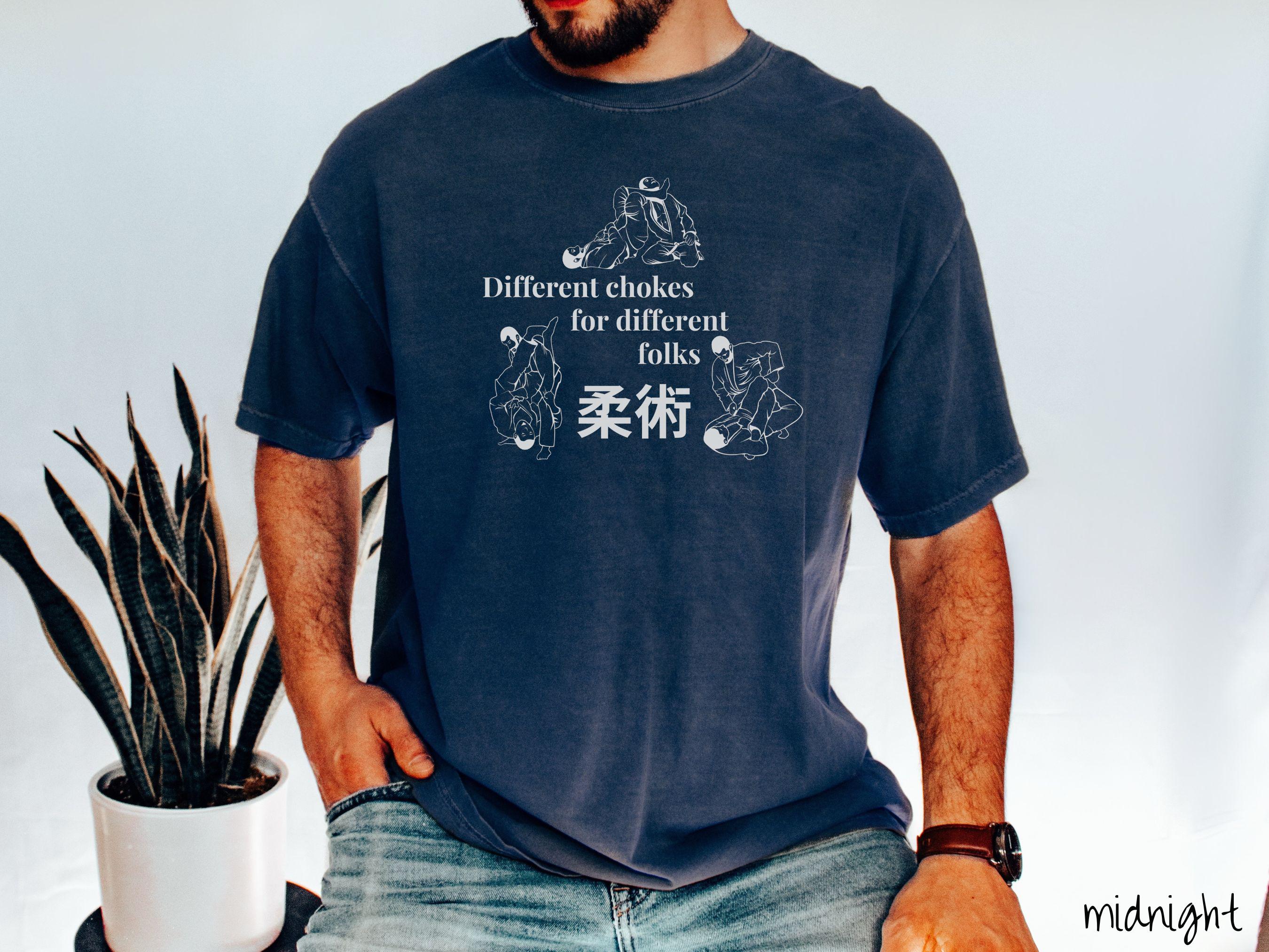 A t-shirt featuring three line art illustrations of Jiu-Jitsu grappling moves. The text reads 'Different chokes for different folks' with Japanese Kanji for 'Jiu-Jitsu' in the center."