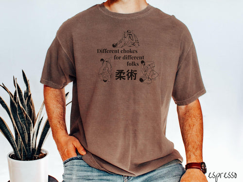 A t-shirt featuring three line art illustrations of Jiu-Jitsu grappling moves. The text reads 'Different chokes for different folks' with Japanese Kanji for 'Jiu-Jitsu' in the center."